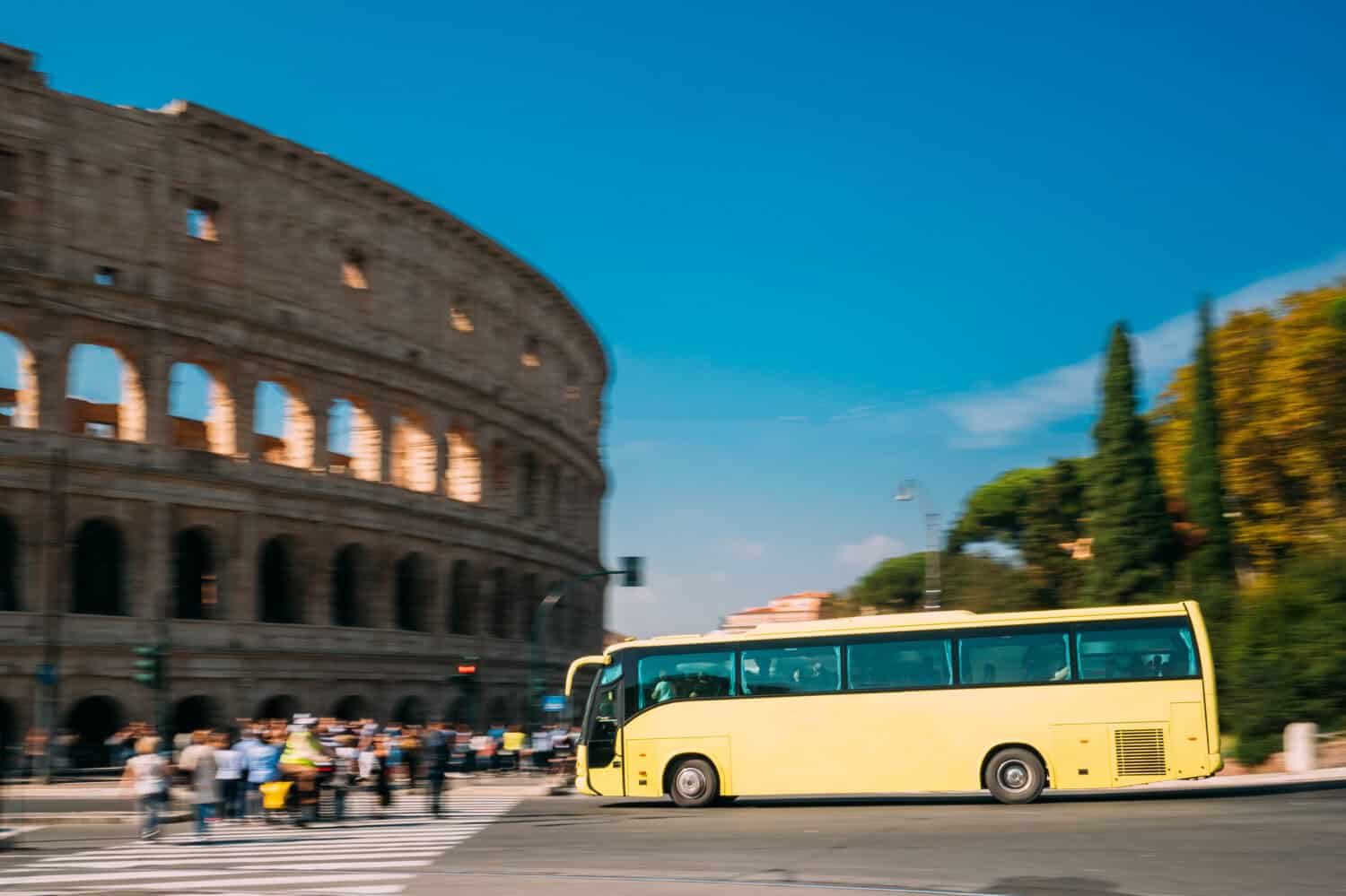 Rome, Italy. Colosseum. Yellow Bus Moving On Street Near Flavian Amphitheatre.
