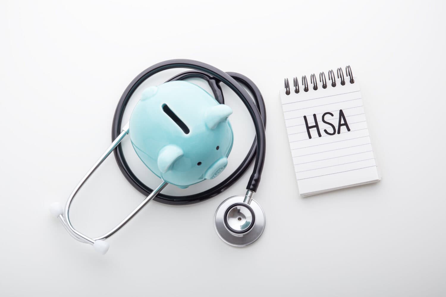 HSA word on note pad with piggy bank and stethoscope, health saving account, hsa concept