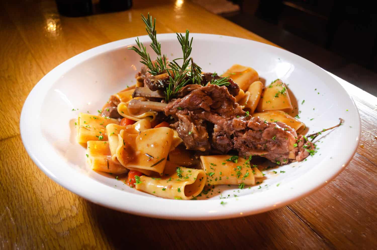 close up of traditional italian dish, paccheri pasta with slow cooked pork short ribs, eating in a fine dining italian restaurant, cool ambience, sharing with loved ones