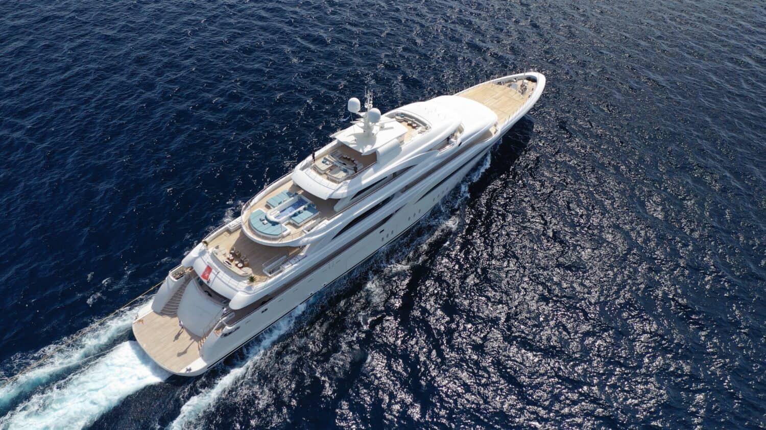 Aerial drone photo of beautiful modern super yacht with wooden deck cruising in high speed deep blue open ocean sea