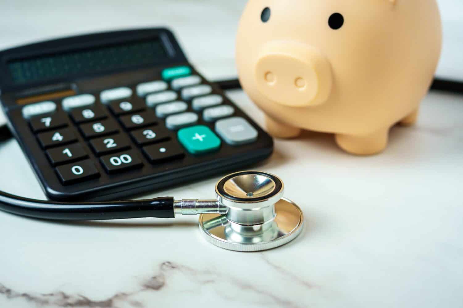 A piggy bank with a calculator and stethoscope showcases the financial aspect of healthcare.
