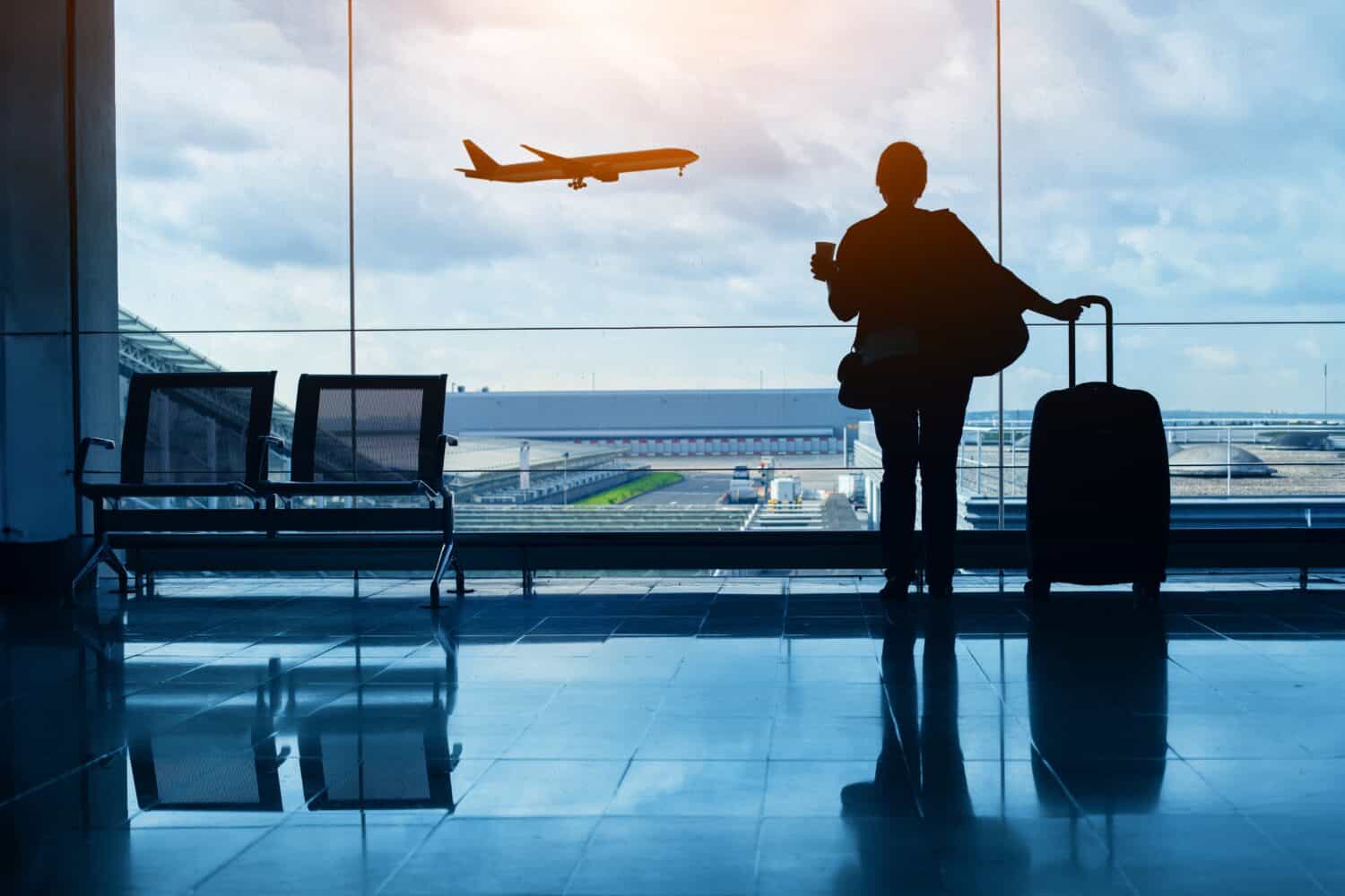 travel by plane, woman passenger waiting in airport, silhouette of passenger watching aircraft taking off