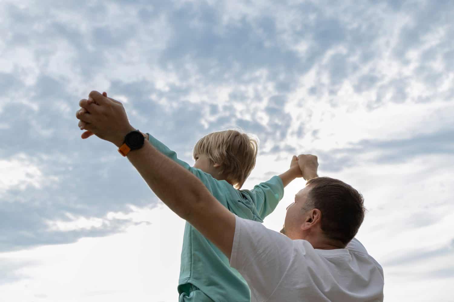 Dad holds his son hands, giving him the strength to fly in life. concept of freedom and self-confidence. family time, happy fatherhood, childhood. father's day, son's day. The joy of communication
