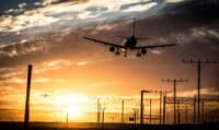 Airplane landing on the track. Plane flying over the airport with beautiful sunset background