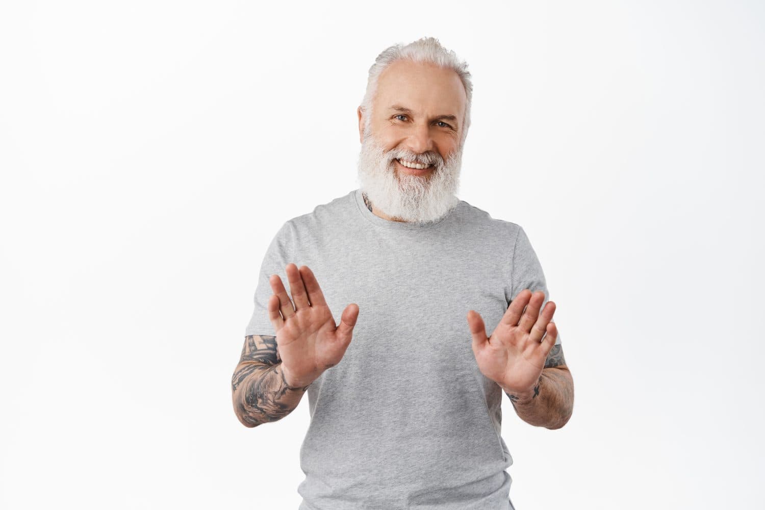 No thanks. Happy smiling old man with tattoos shaking hand to refuse, reject offer, politely refuse something, standing in gray t-shirt on white background