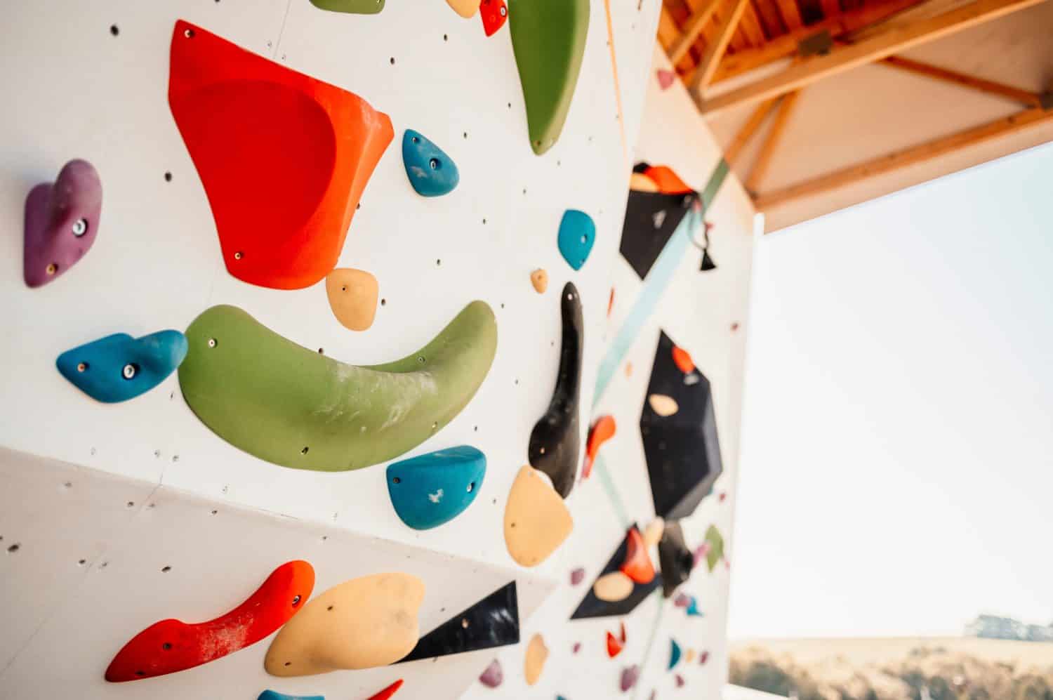 Wall with climbing holds in gym. Practicing rock-climbing on a rock wall outdoor. Xtreme sports and bouldering concept. rock climber climbs on a rocky wall.