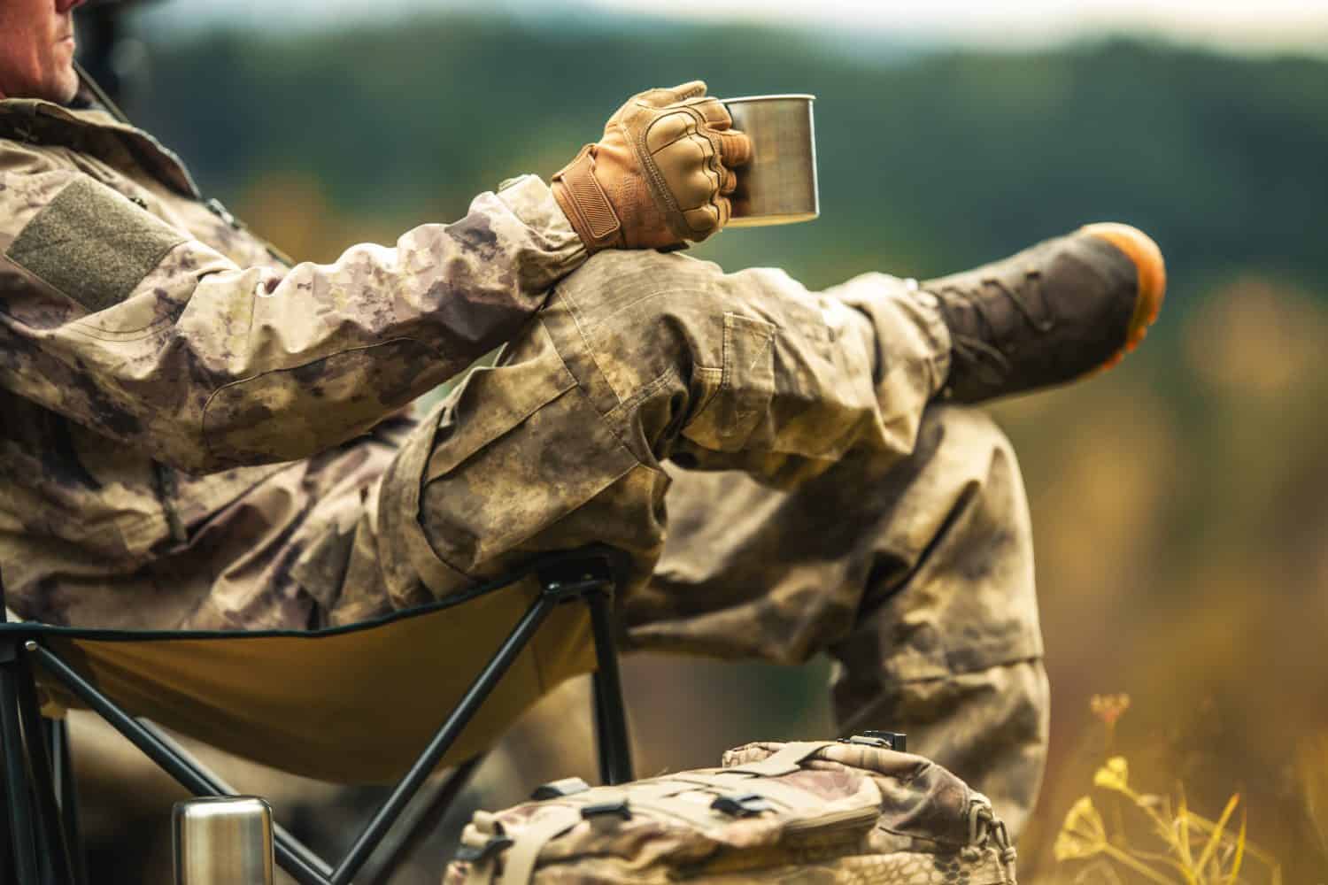 A Hunter Relaxing During Hunting Trip Drinking Coffee From His Metal Made Mug