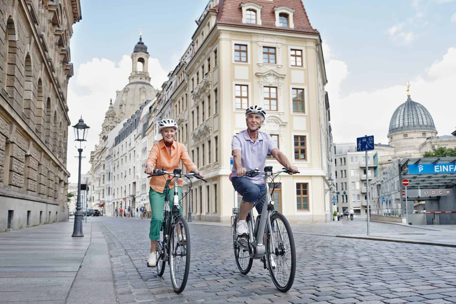 Elderly tourists riding an electric bicycle against the Frauenkirche cathedral in Dresden, Germany