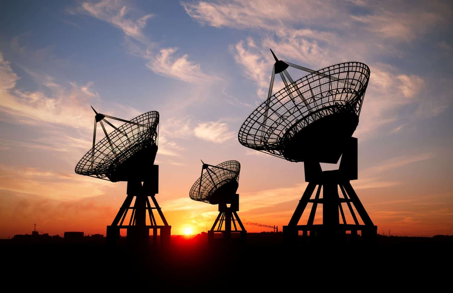 Three satellite dishes at sunset