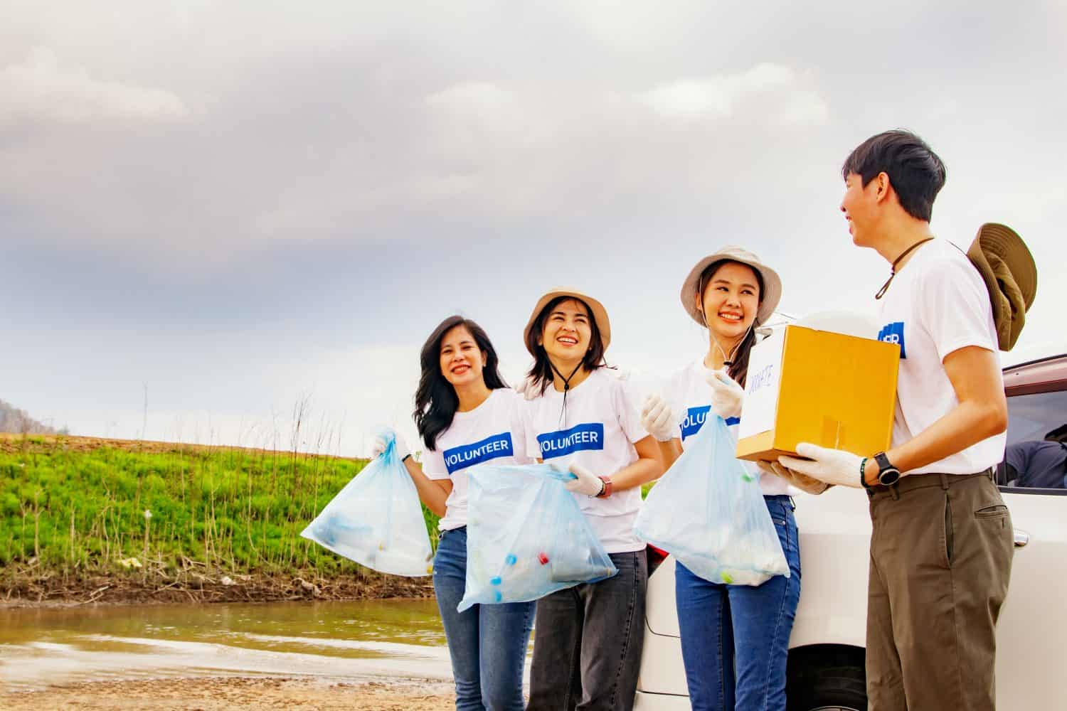 Male volunteers holding donation boxes and dividing into groups female teams holding trash bags during good deeds nature conservation project volunteers tourist areas natural water resources.