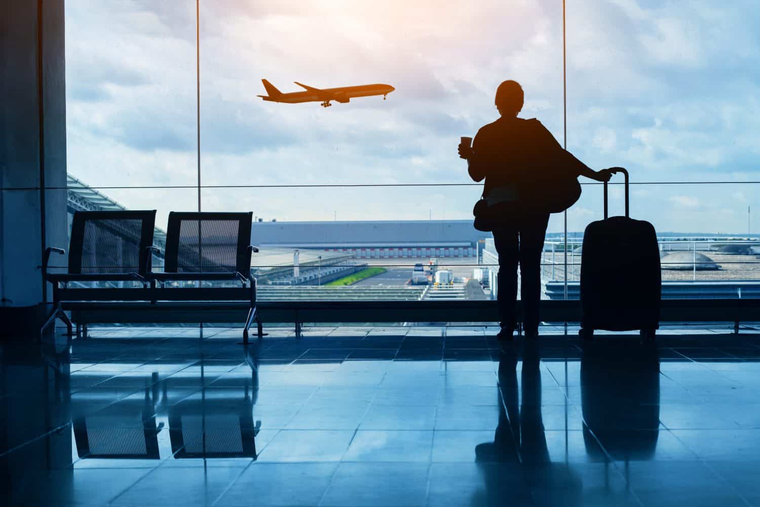 airplane travel, female passenger waiting in airport, silhouette of passenger watching aircraft take off