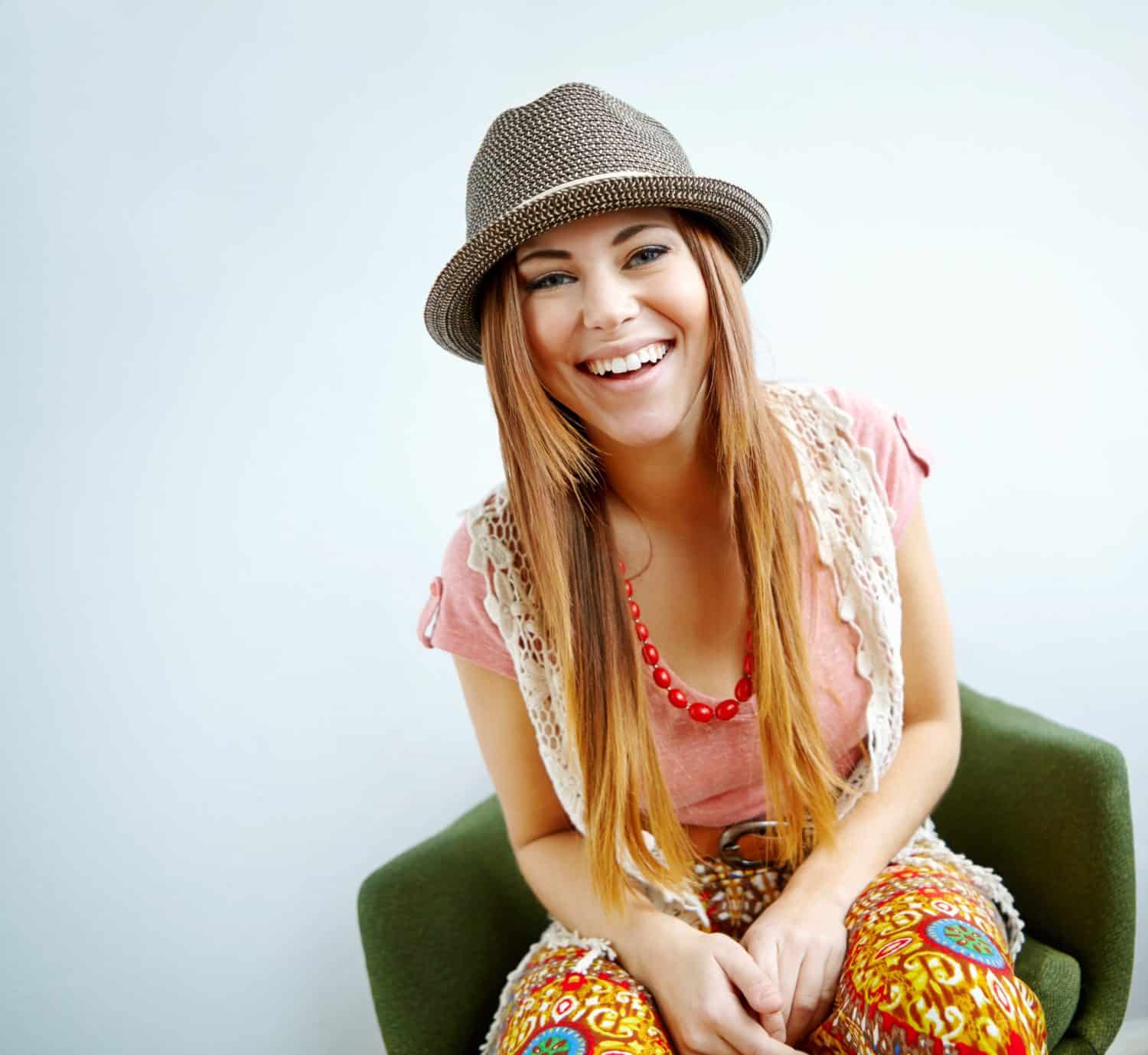 Happy woman, vintage fashion and home portrait, confidence and quirky style on white background. Female person funky clothes and laughing on mockup space, hipster proud and relax on chair in lounge