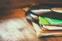 records stack with record on top over wooden table. vintage filtered