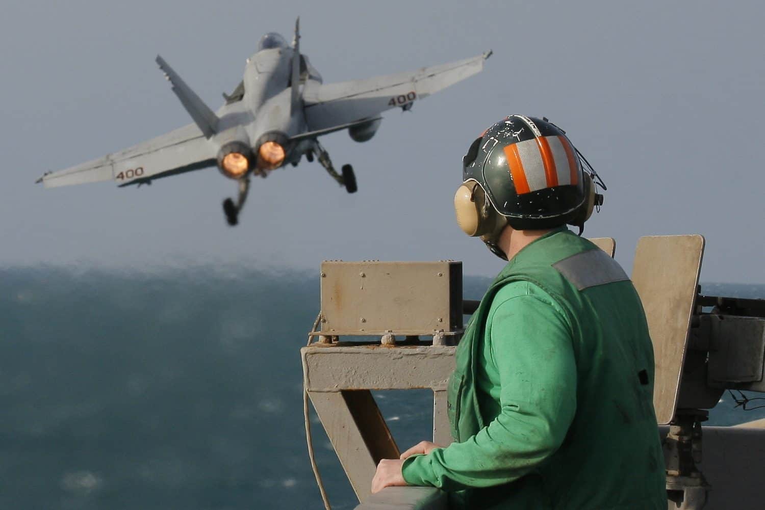 A catapult crew member watches the launch of an F/A-18C Hornet from the nuclear-powered aircraft carrier USS Enterprise