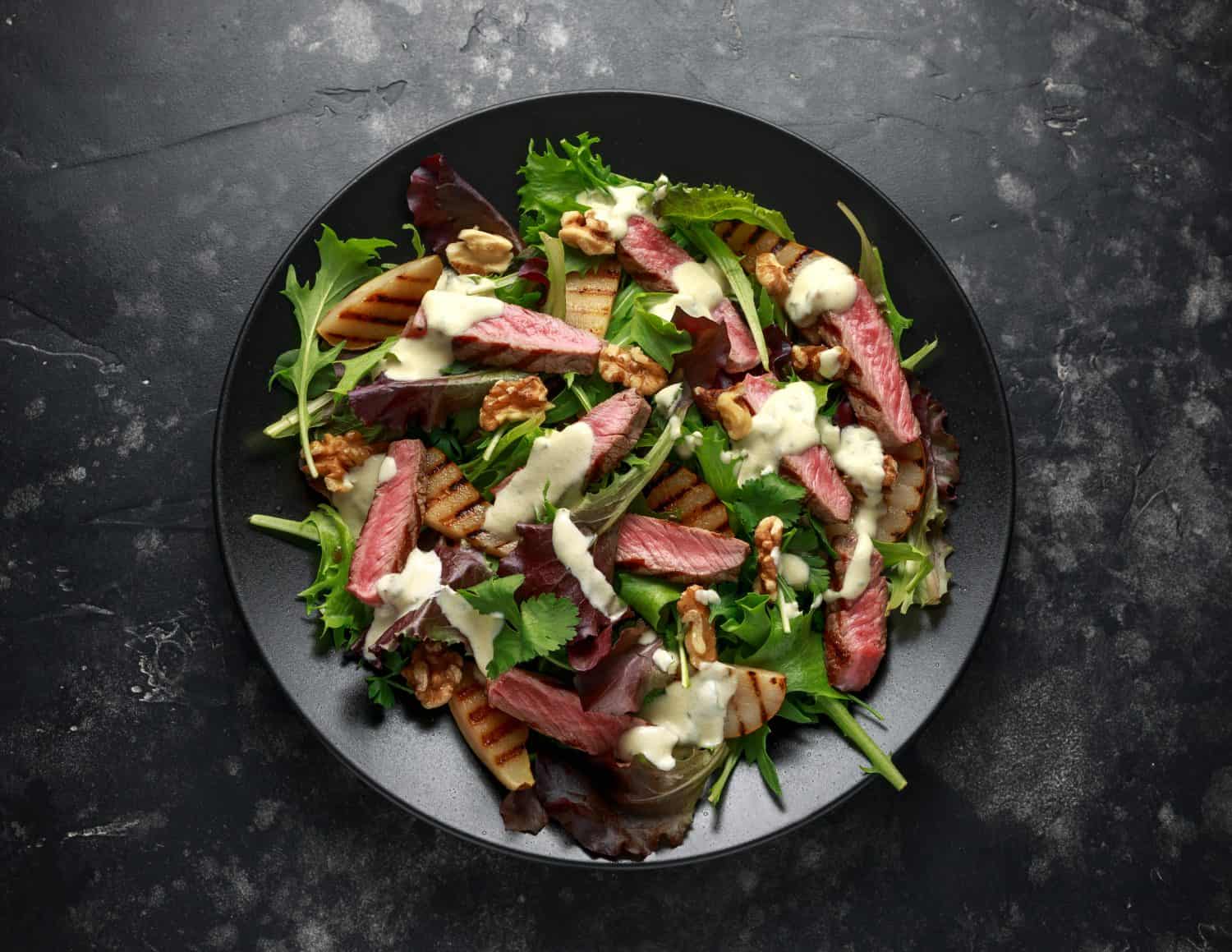 Grilled roast beef salad with pears, walnuts and green vegetables and blue cheese dressing. healthy food.