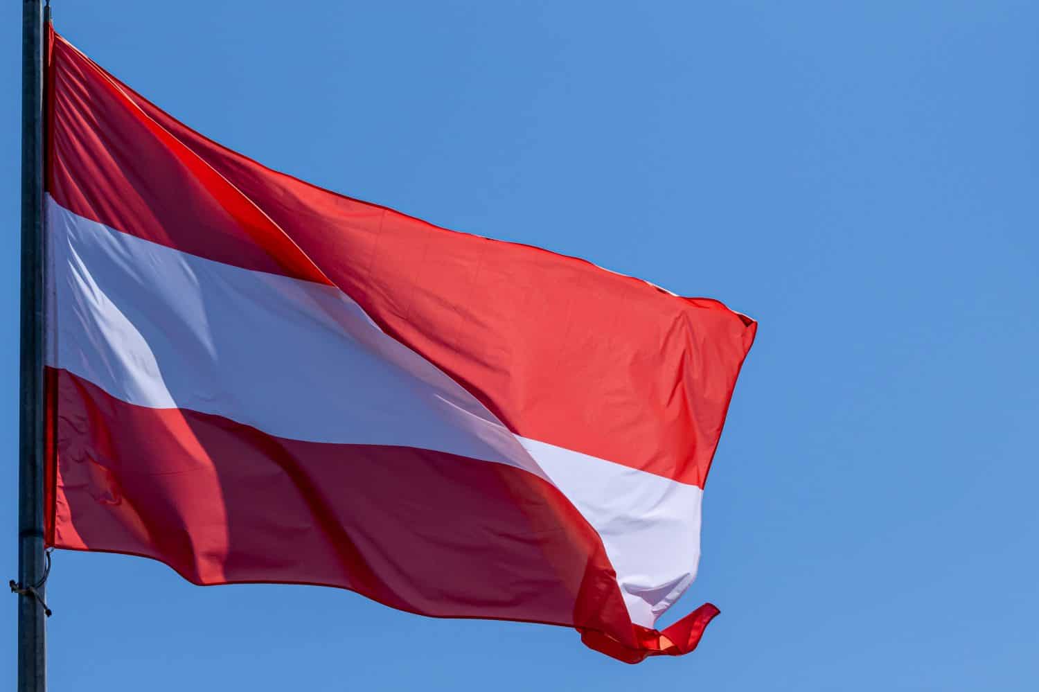 Austrian national flag waving on blue sky background. Republic of Austria, AT