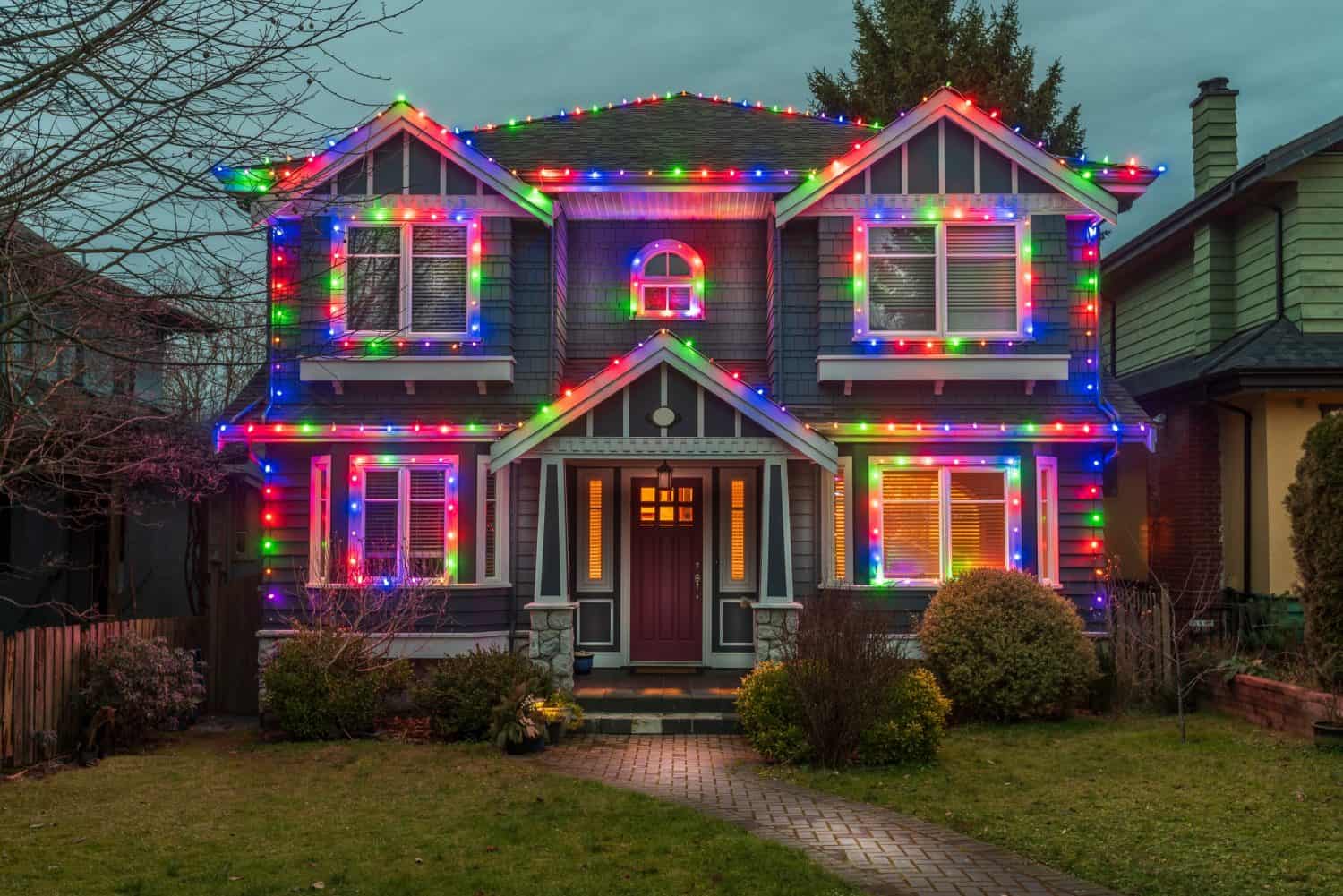 Luxury two-story stucco house with garage door, big tree and beautiful Christmas night decorations in Vancouver, Canada, North America. Night in December 2021.