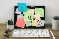 I Quit text written on sticky note, on computer screen.