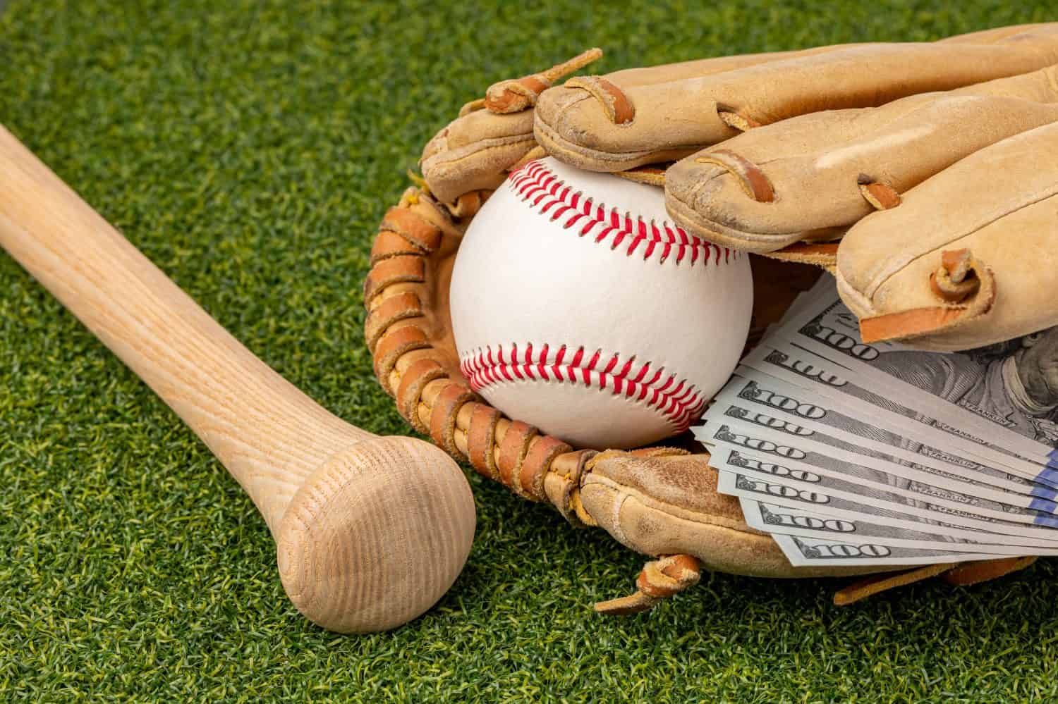 Baseball, glove and wooden bat with cash money. Baseball salary expenses and sports gambling concept.