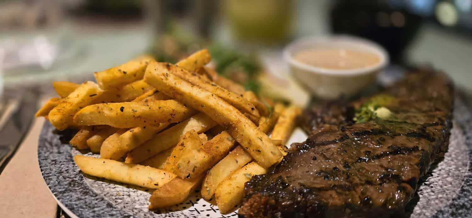 Grilled tenderloin medium rare served with potatoes and salad with black pepper mushroom sauce in a restaurant