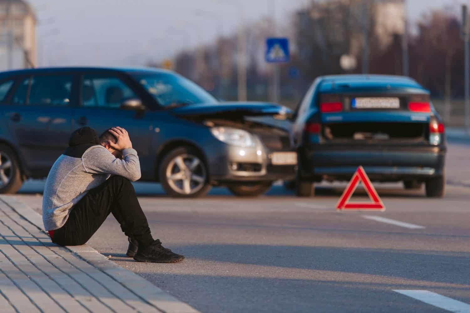 A man looks desperate after two cars crashed on the road at his fault