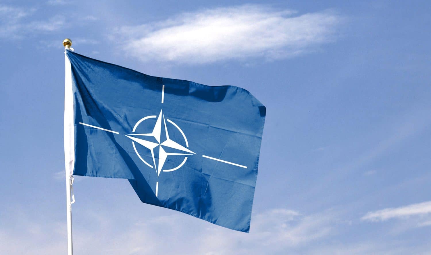 NATO flag on cloudy sky. flying in the sky