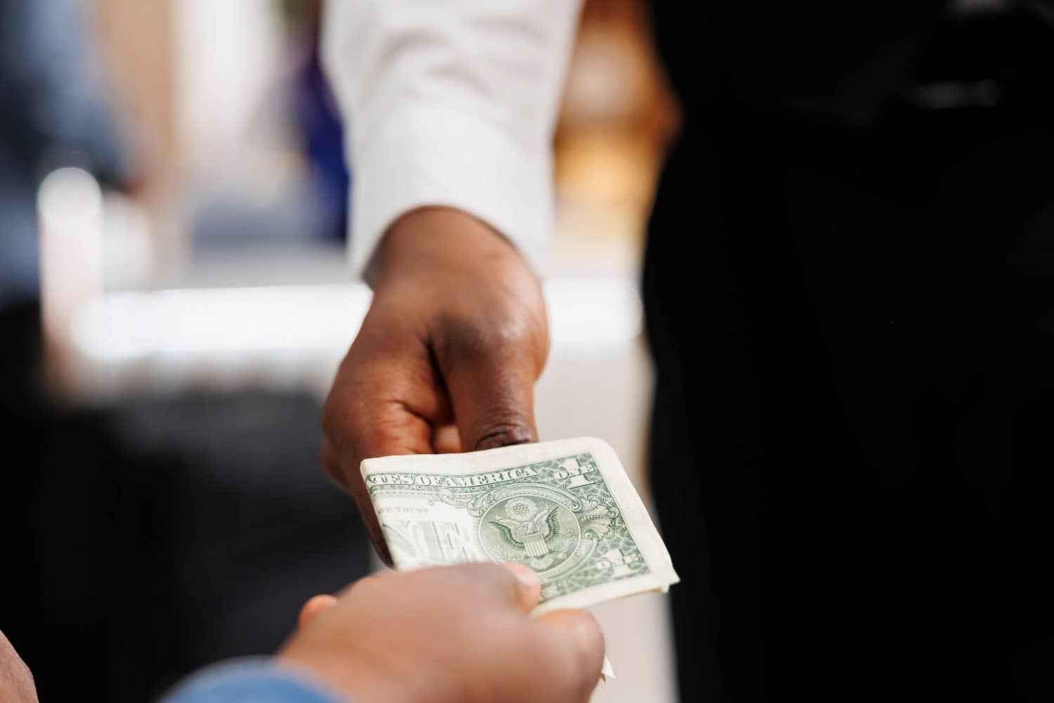 Close-up of hospitality worker accepting cash payment taking money from customer. The hotel guest owns money by paying for services at the resort, tipping the waiter at the bar or restaurant