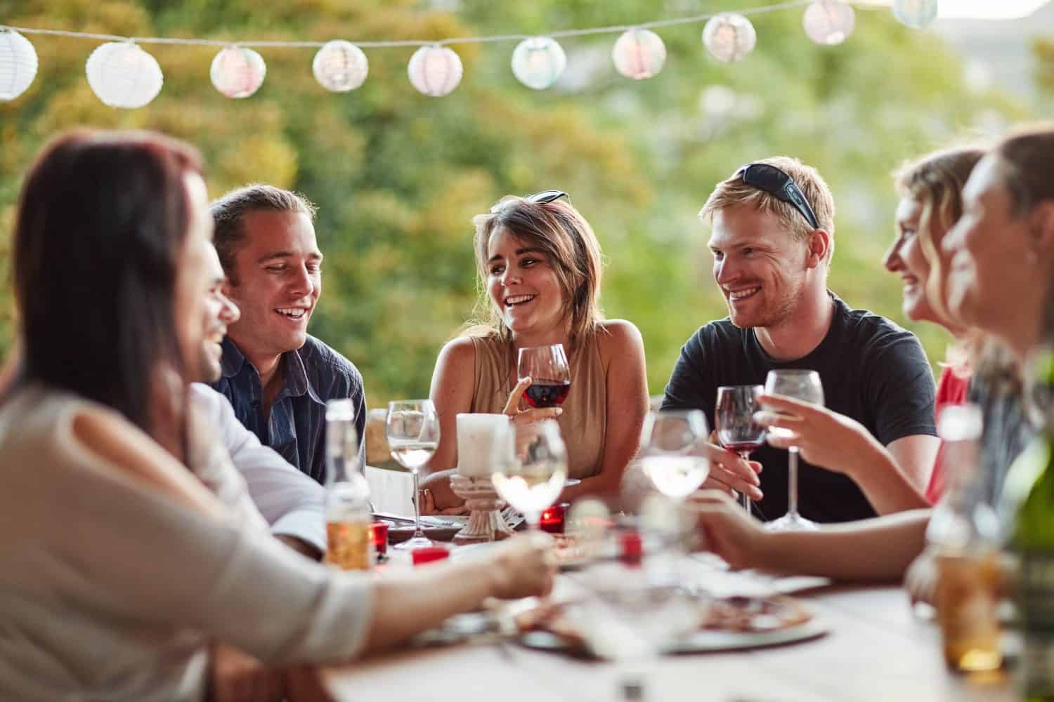 Friends, group and pizza dinner, celebration and young people together with drinks. Vacation, patio at home and get together outdoors with alcohol, friendship and food at a social event with a smile