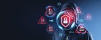 A hooded figure, representing a hacker, is central to the image. Their face is obscured by a glowing red and blue shield icon with a white padlock. Around the figure are multiple holographic red and blue circular icons with white symbols: a cloud server with an alert, a document with an alert, a key, a dollar sign on a card with an alert, an email with an alert, an ID card with an alert, a globe, a refresh symbol, an eye with a plus sign, and a password field. The background is a dark blue with subtle binary code overlay. The overall impression is one of digital security threats.