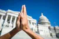 Hands held together in prayer in front on Capitol Building in Washington DC, USA