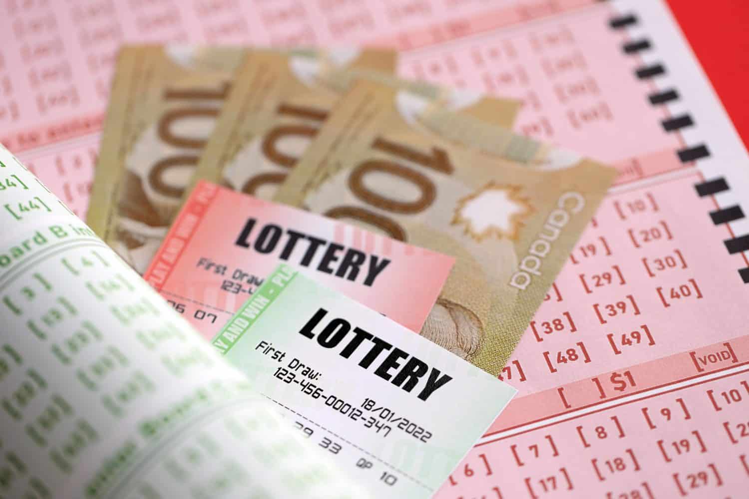 Lottery tickets lies with canadian dollars on gambling sheets with numbers for marking to play lottery. Lottery playing concept or gambling addiction