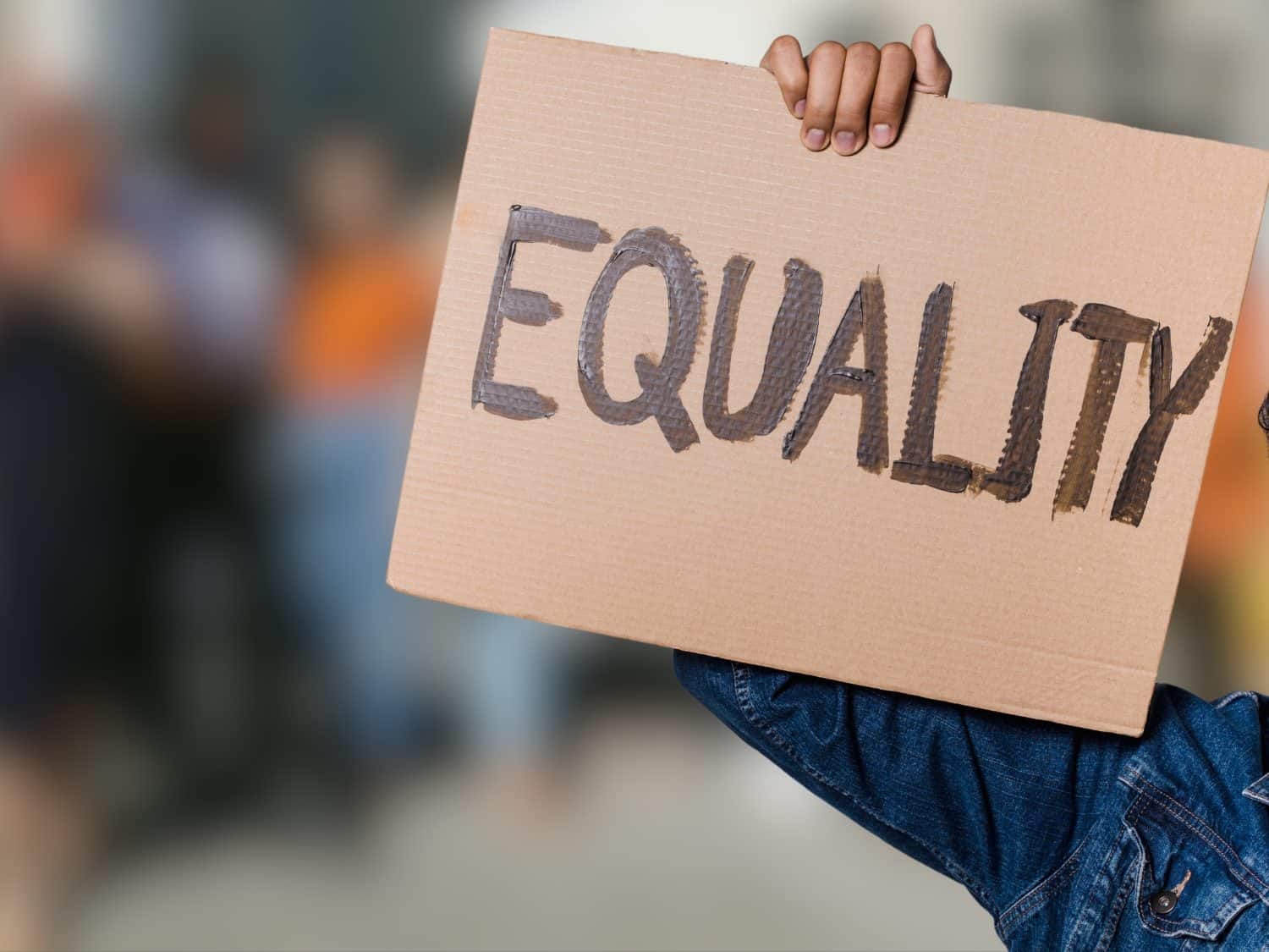 A protester holds up a cardboard sign reading 