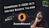 A man wearing glasses and a black baseball cap, with a slight beard, looks thoughtfully upwards, touching his chin. In the bottom left, a black street sign reads 'WALL ST 105-120 → ST'. A large orange and black SoundHound logo is centrally placed. A black text box overlay at the top reads 'SOUNDHOUND AI (SOUN) GETS ANOTHER MASSIVE TAILWIND'. In the top right corner, a green and black 24/7 WALL ST logo is visible. The background is a dark blue with a subtle, light blue line graph resembling a stock chart.