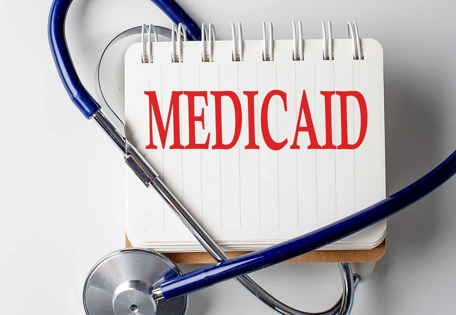 MEDICAID word on a notebook with medical equipment on background