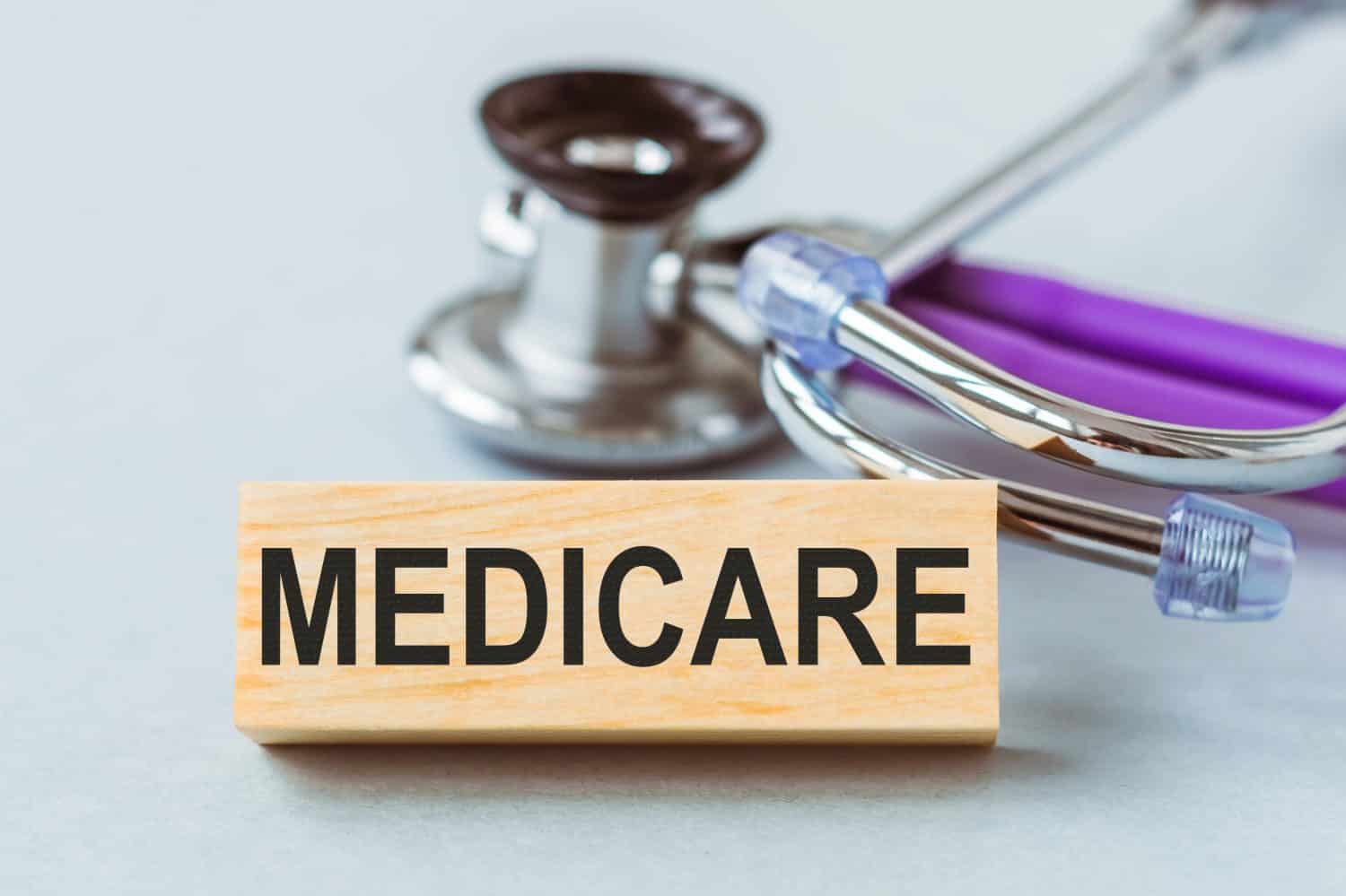 Medicare word written on wooden block on white table with stethoscope