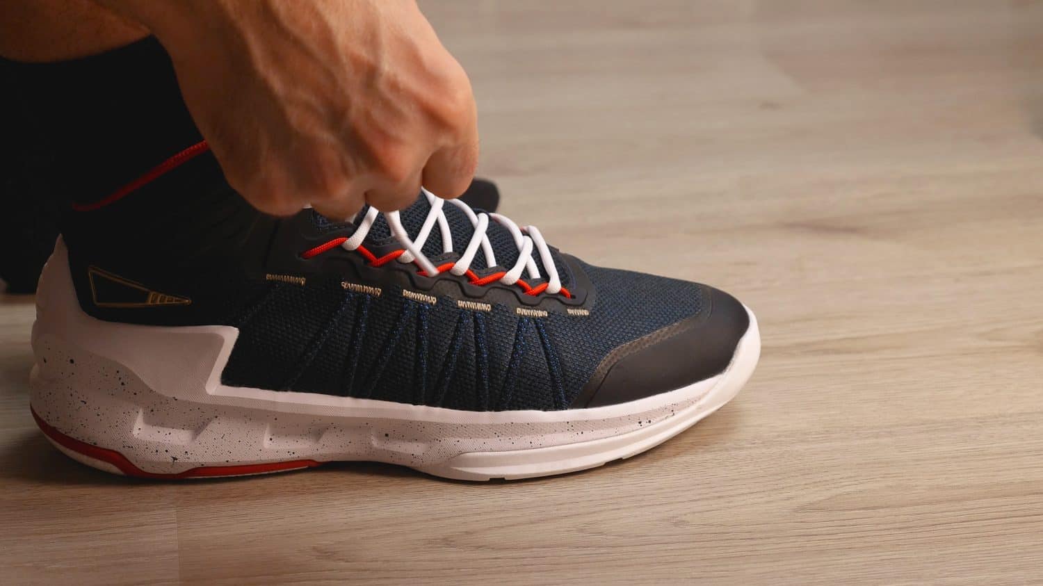 Close-up of black and white basketball shoes. Men's hands are tying the laces. Preparing for a training session or a walk
