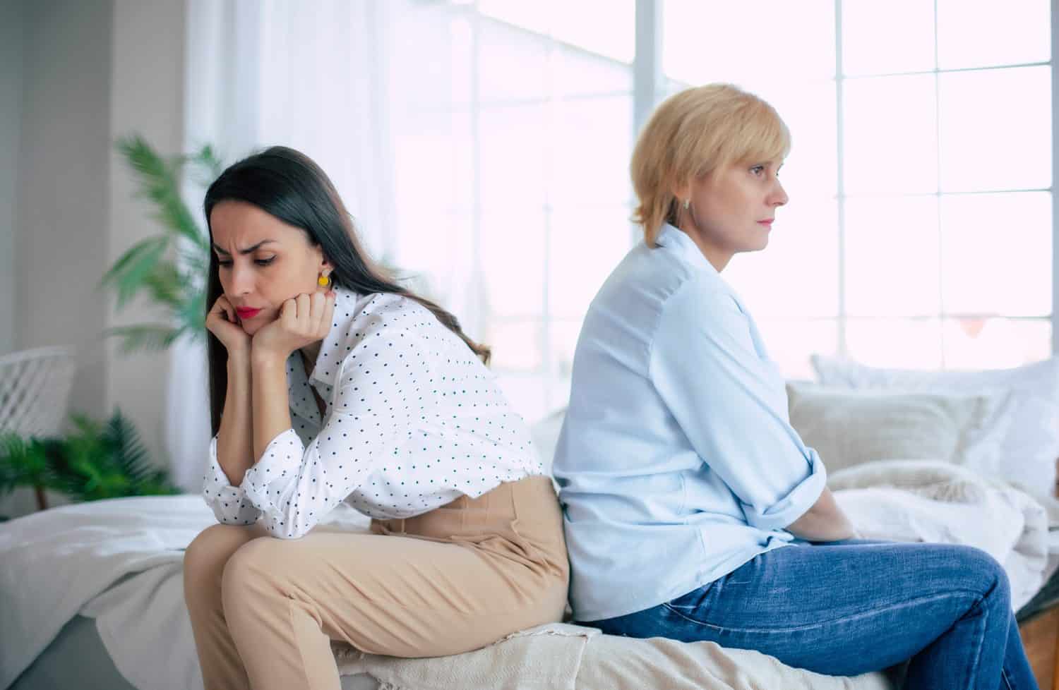 Offended adult daughter and mature mother sit back to back avoid talking after quarrel, stubborn two generations of women ignore each other after conflict, misunderstanding concept