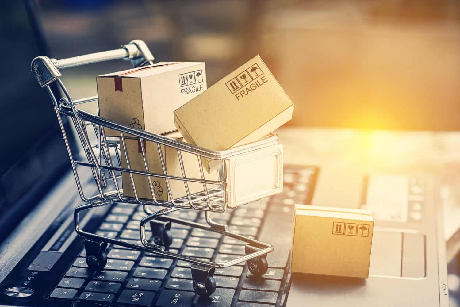 Paper boxes in a shopping cart on a laptop keyboard. Ideas about e-commerce, e-commerce or electronic commerce is a transaction of buying or selling goods or services online over the internet.