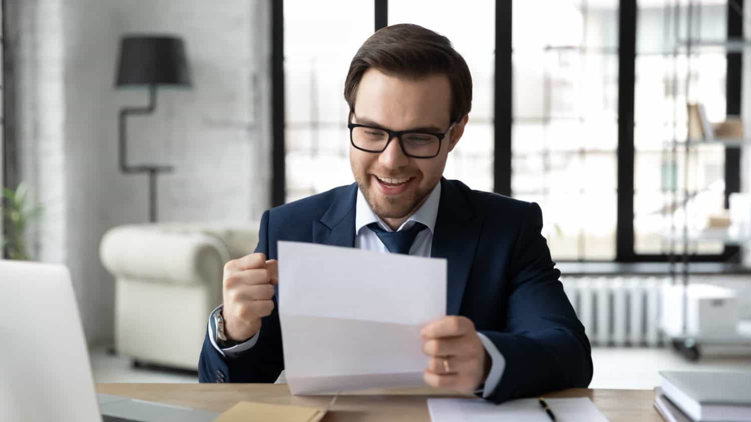 Happy businessman learning good news, reading letter, getting document from bank with approval loan or mortgage, receiving insurance notice, professional certificate. Paperwork, correspondence concept