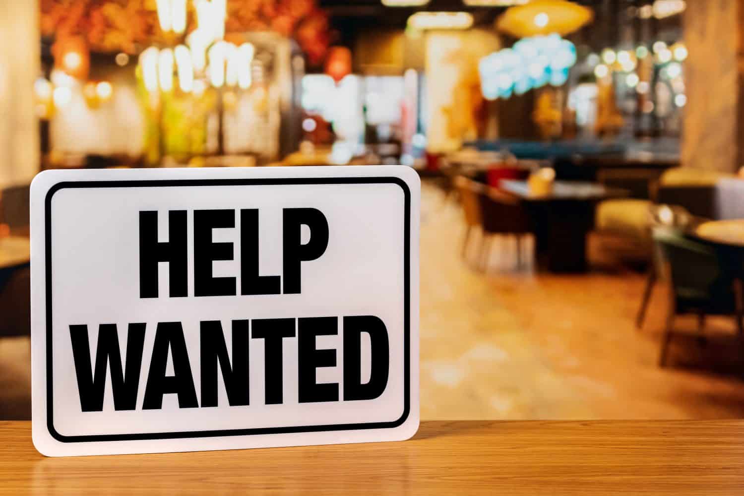 Help wanted sign inside restaurant. Food service industry jobs, labor shortage and unemployment concept.