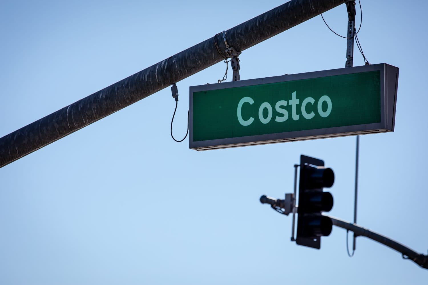 A green street Costco sign over an intersection, blue clear sky