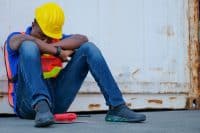 American African engineer or technician worker man sit close to cargo container and he look tired and sleepy or lost job. Concept of good system and manager support for better industrial business.