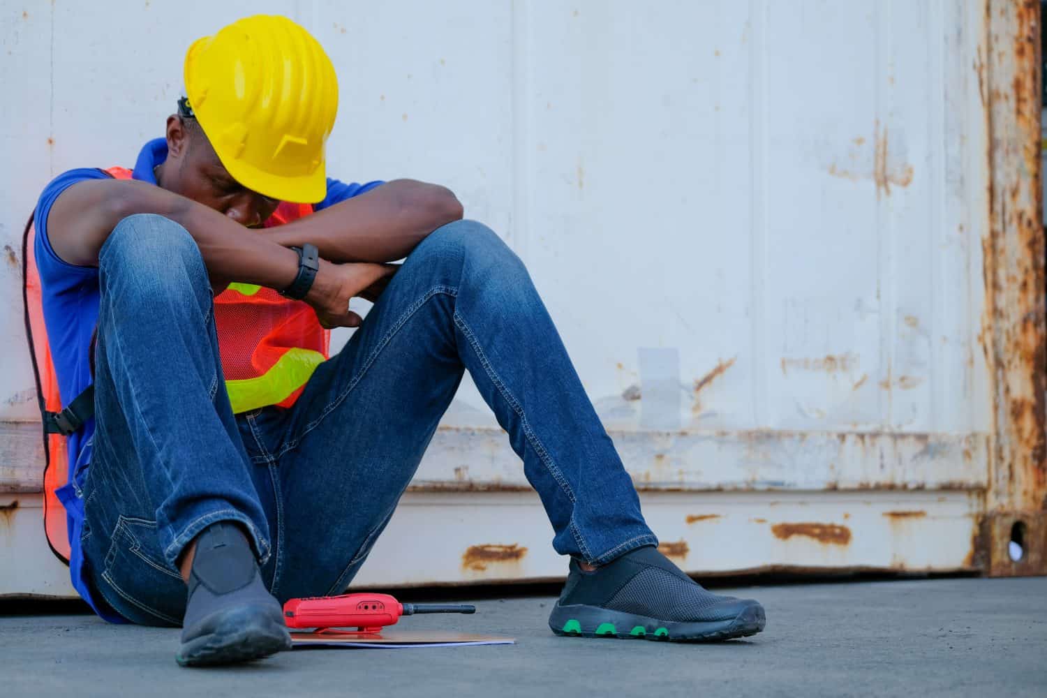 American African engineer or technician worker man sit close to cargo container and he look tired and sleepy or lost job. Concept of good system and manager support for better industrial business.