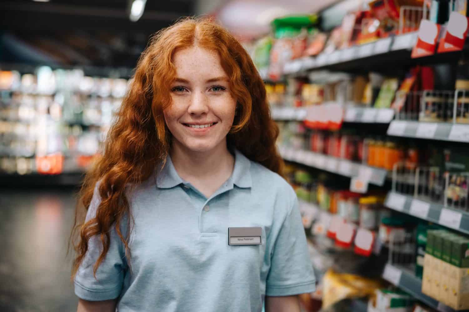 Portrait of a young woman working at supermarket during holidays. Woman doing a part time job grocery shop.