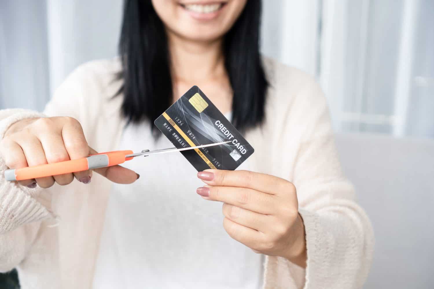 Asian woman hand holding scissors cutting credit card financial, debt freedom concept