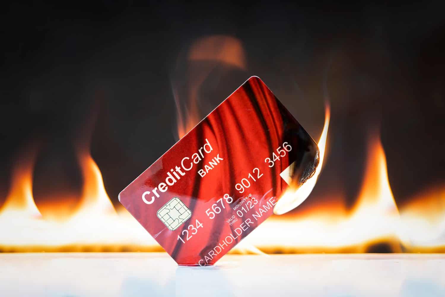 Bank credit card in flames on black background. Concepts of the collapse of financial markets and the credit and financial system. Sanctions and disconnection from the swift system.