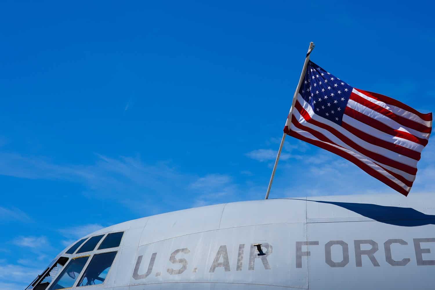 The flag of America is hanging over a military airplane part of the US Air Force. Army industry in this difficult times of war.