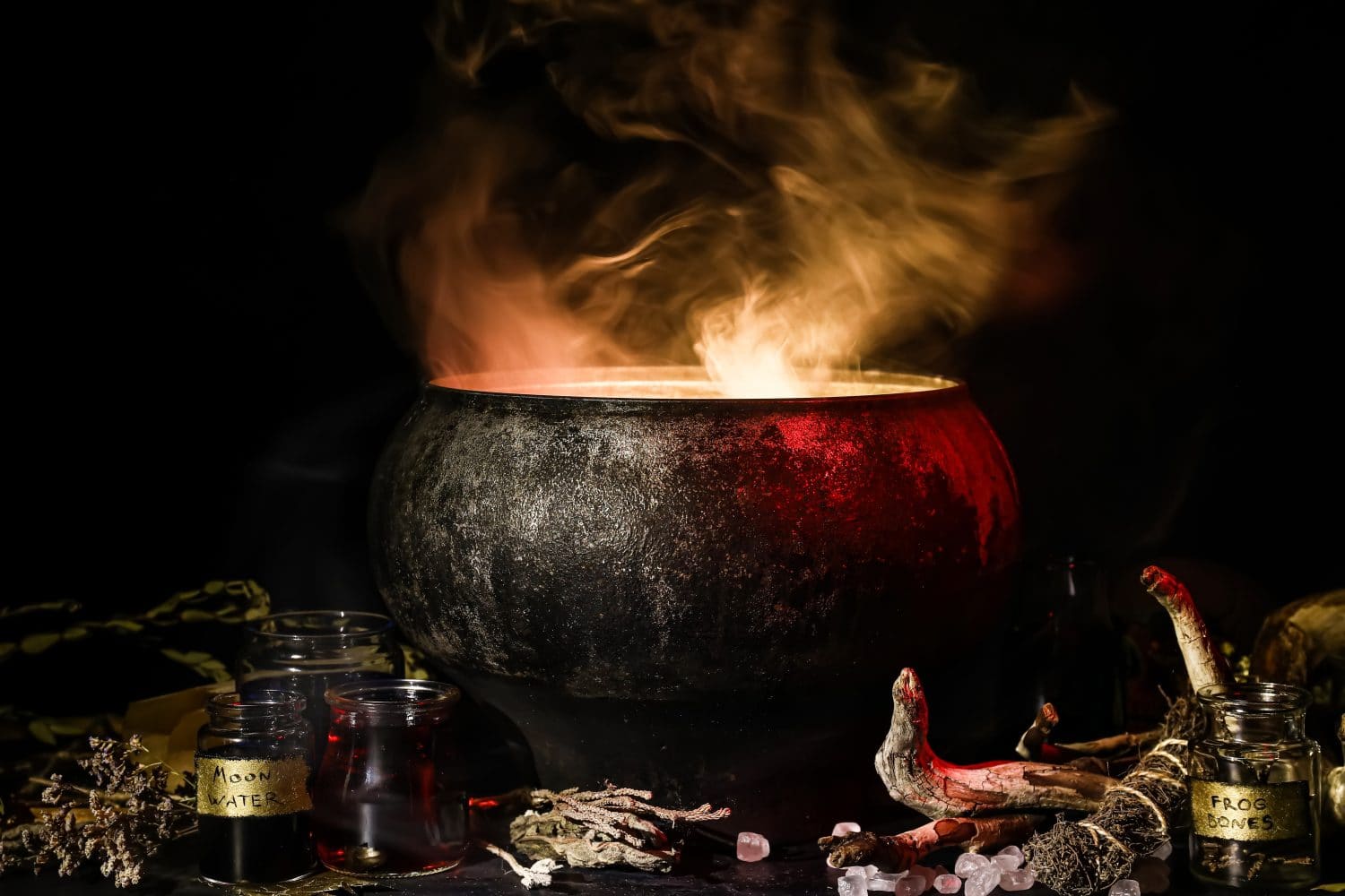 Witch's cauldron with potion and different magic attributes for ritual on dark background