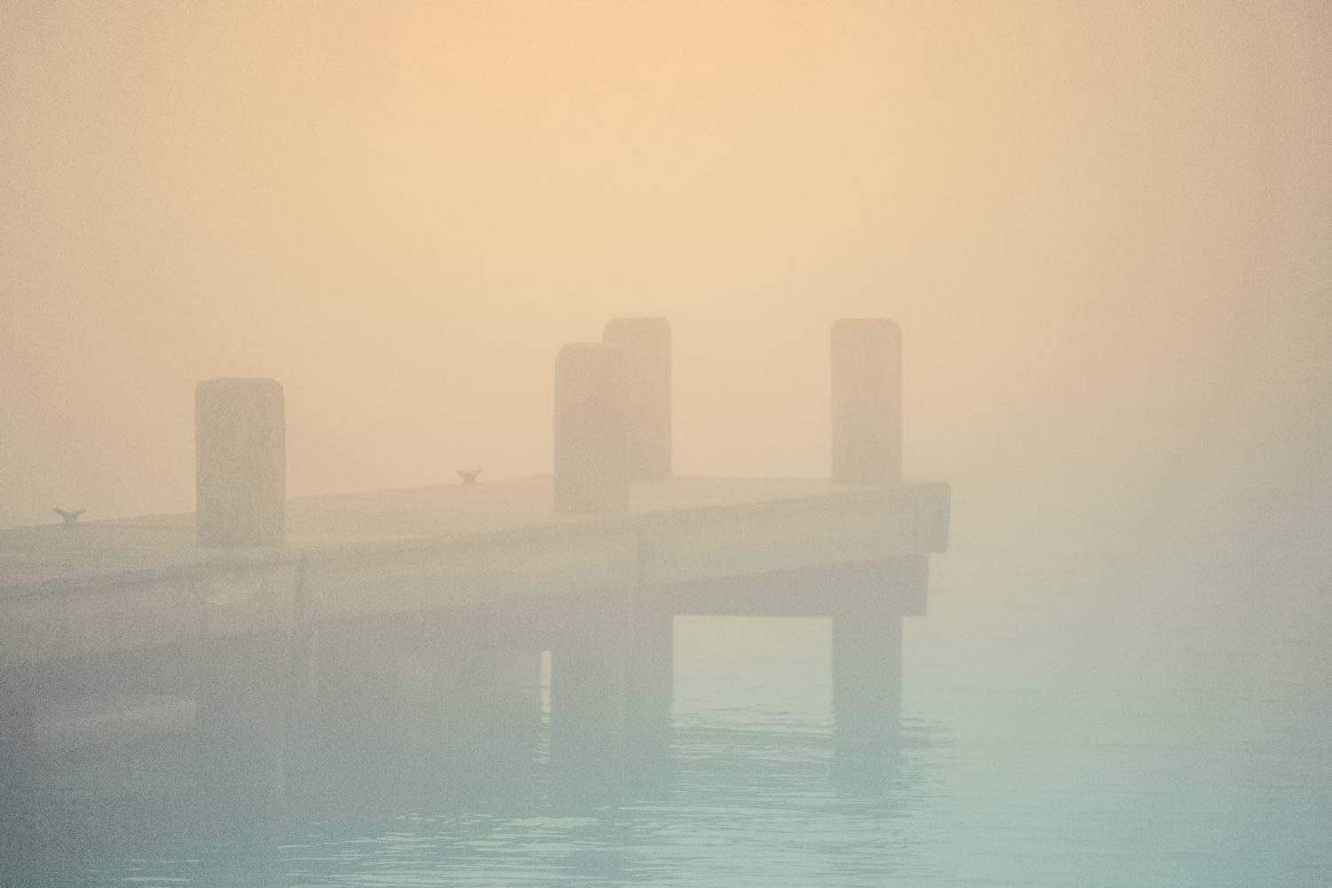 Nantucket Harbor Fog Seascape on an autumn morning with pastel toned silhouette of the dock in Massachusetts, United States, an abstract minimalist backgrounds for mysterious or moody themes