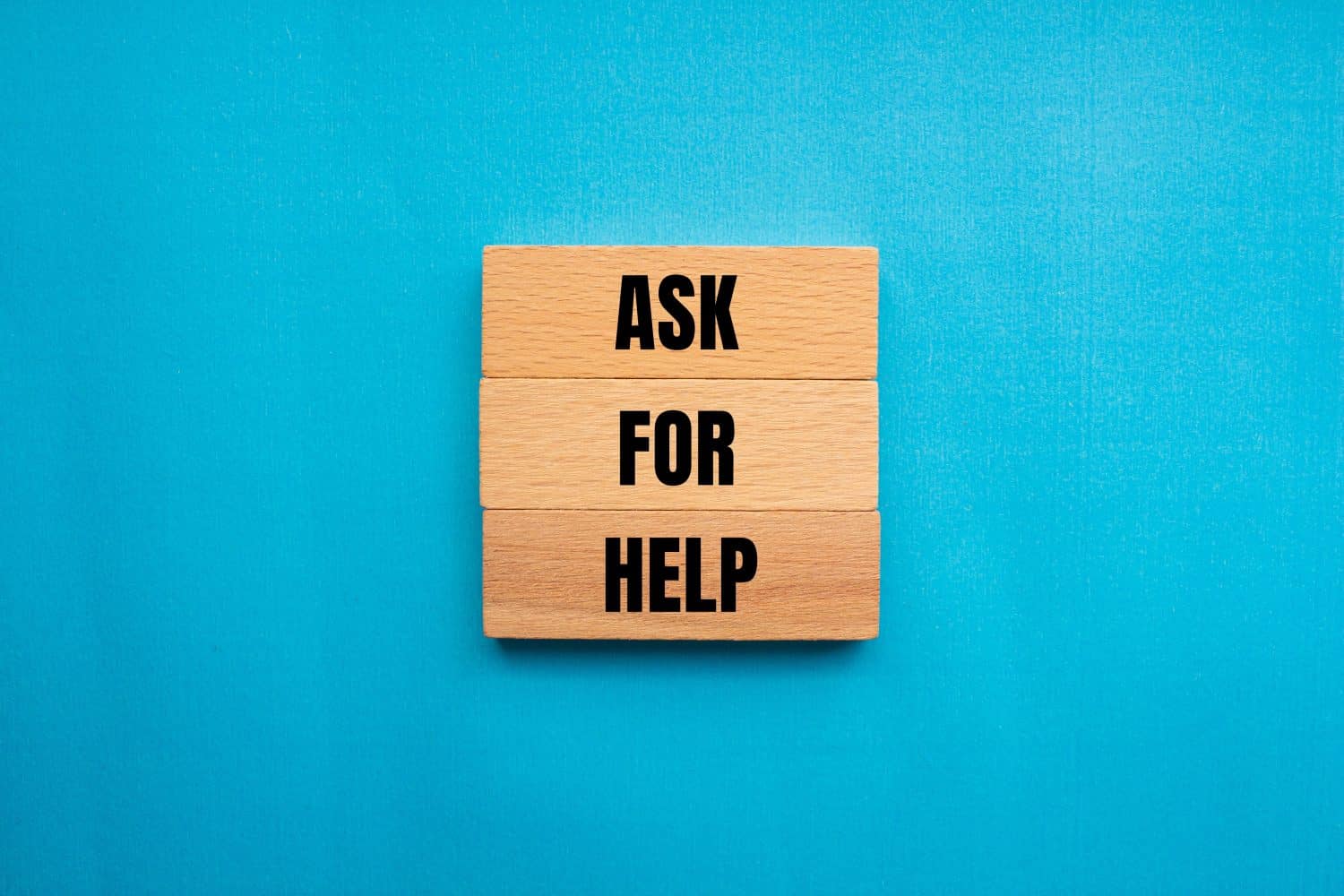 Ask for help words written on wooden blocks with blue background. Conceptual ask for help symbol. Copy space.